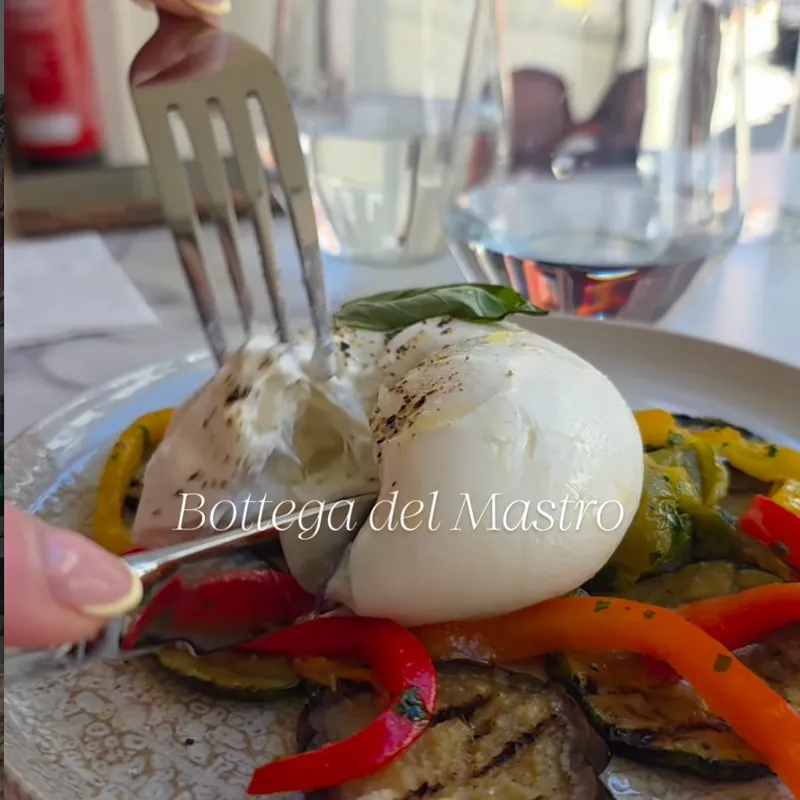 Cutting into fresh burrata with grilled vegetables